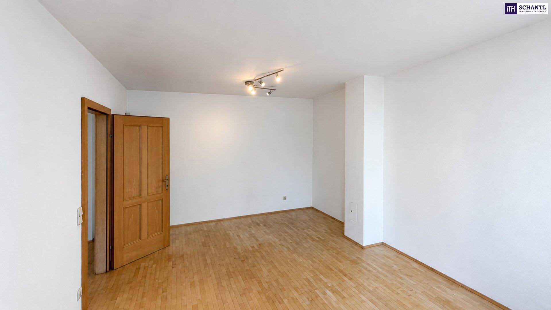 Geräumiges, unmöbliertes Wohnzimmer mit hellem Holzboden und weiß gestrichenen Wänden.