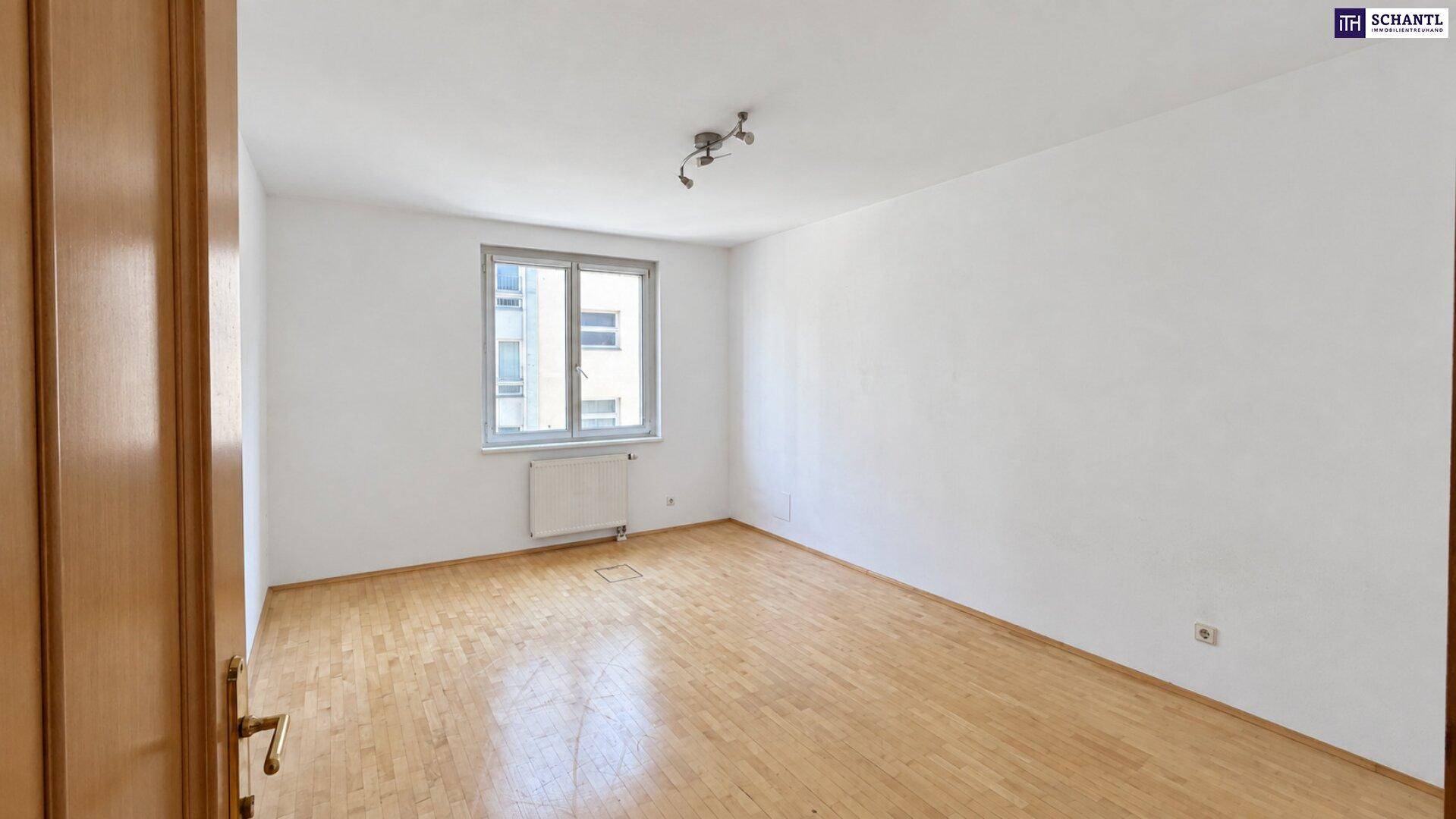 Geräumiges Schlafzimmer mit Holzboden, weiß gestrichenen Wänden und einem großen Fenster.