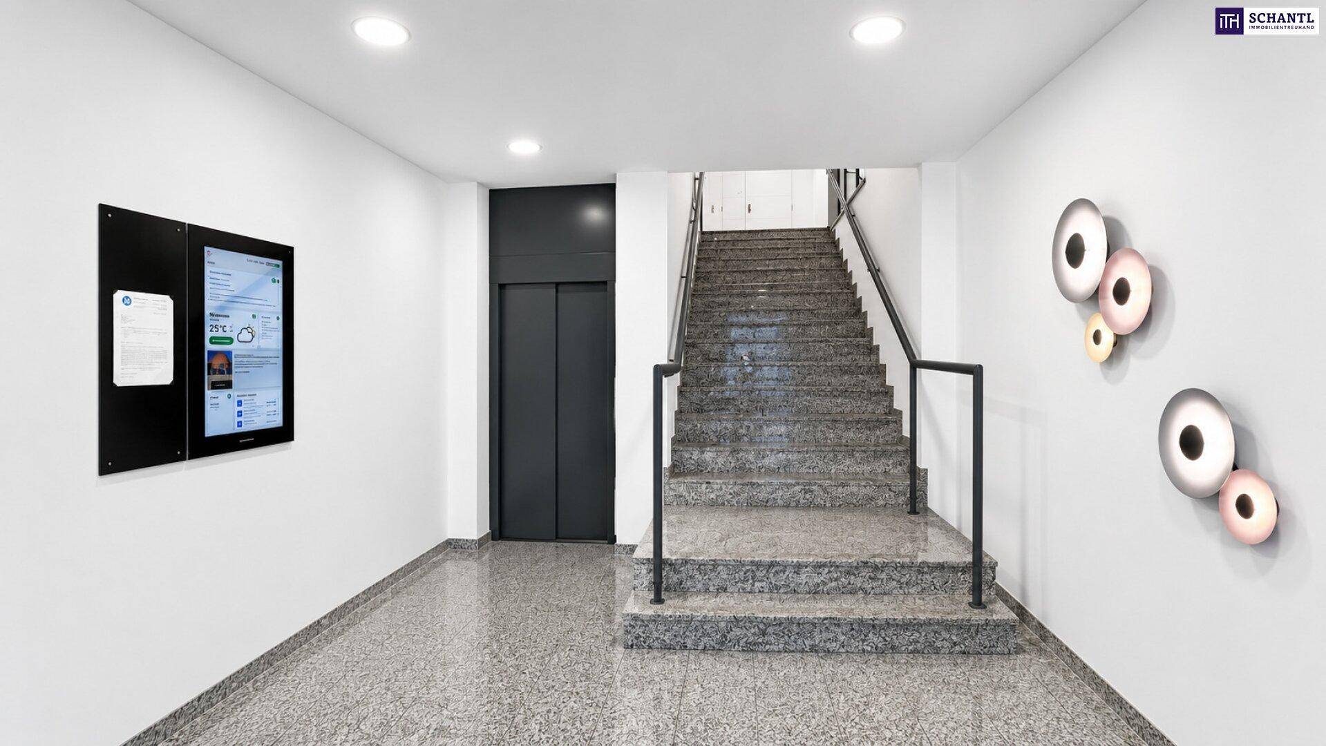 Geräumiger Eingangsbereich mit Treppe, Aufzug und Informationsbildschirmen.