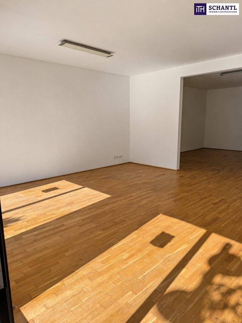 Leerer Geschäftsraum mit Holzboden und weißen Wänden, bereit für individuelle Einrichtung und Nutzung.