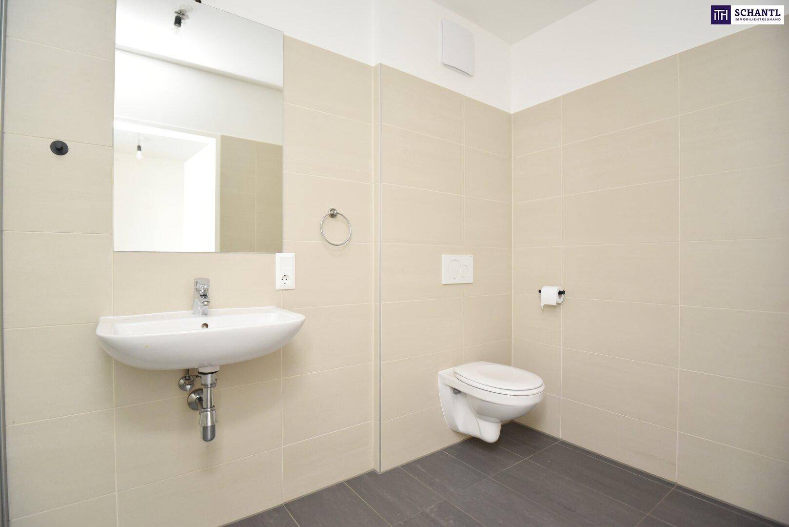 Helles Badezimmer mit wandhängendem WC, Waschbecken und großen, beigefarbenen Fliesen.