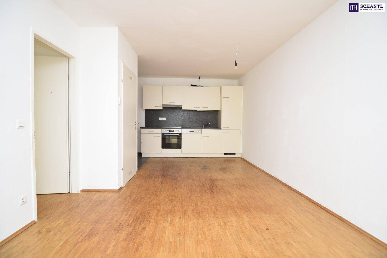 Offene Küche mit hellen Einbauschränken und integrierten Geräten, kombiniert mit Holzboden.