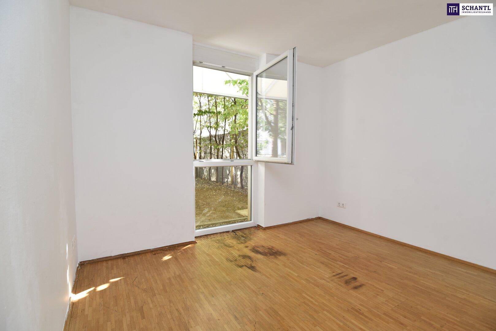 Helles Schlafzimmer mit Holzboden und einem Fenster, das einen angenehmen Blick ins Grüne bietet.