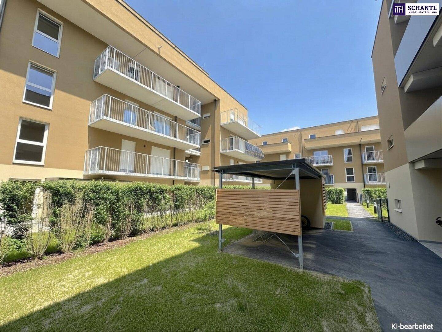 Moderner Wohnkomplex mit Carport, gepflegter Grünanlage und Balkonen unter strahlend blauem Himmel.