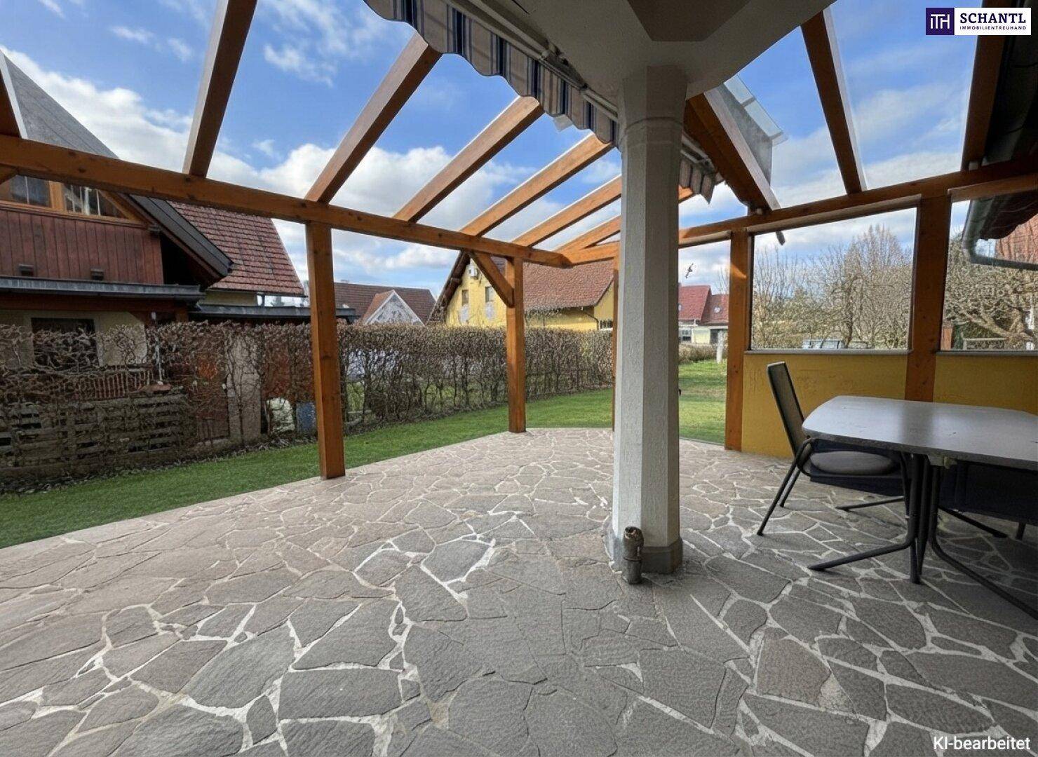 Überdachte Terrasse mit rustikalem Steinboden und Gartenmöbeln, ideal für entspannte Stunden im Freien.