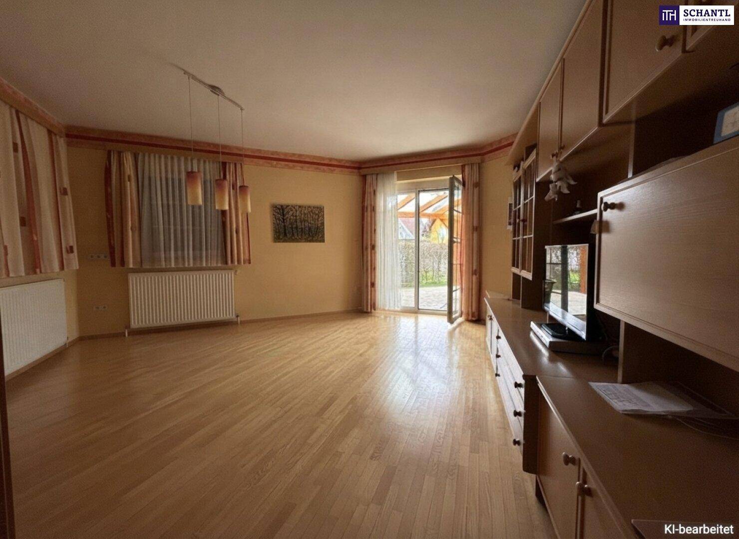 Helles Wohnzimmer mit Parkettboden, großen Fenstern und direktem Zugang zur überdachten Terrasse.