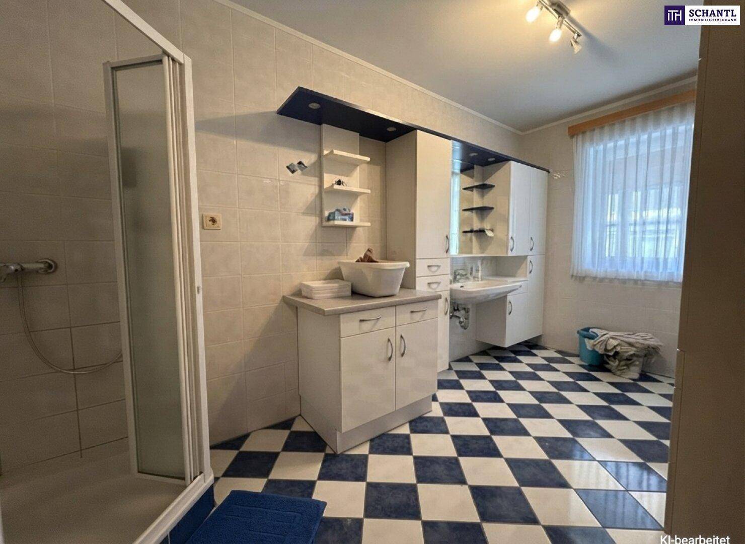 Geräumiges Badezimmer mit Dusche, Waschbecken, viel Stauraum und einem markanten Fliesenboden.