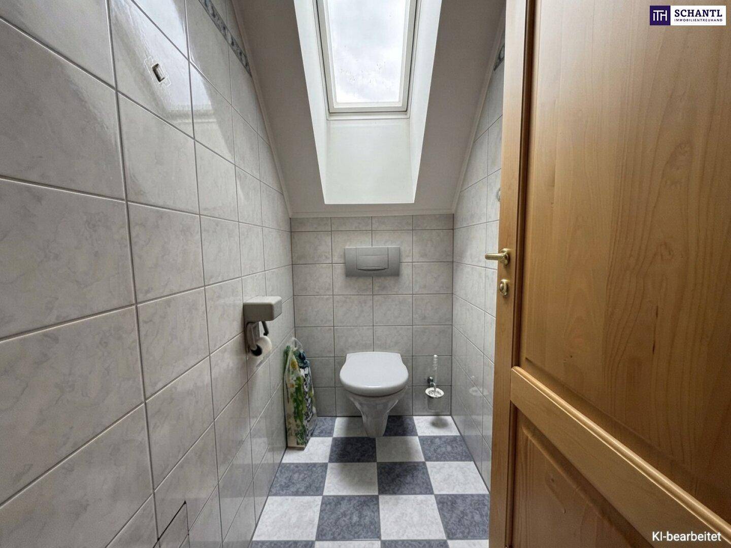 Helles WC mit Fliesenboden, gefliesten Wänden und einem Dachfenster für natürliche Belüftung.