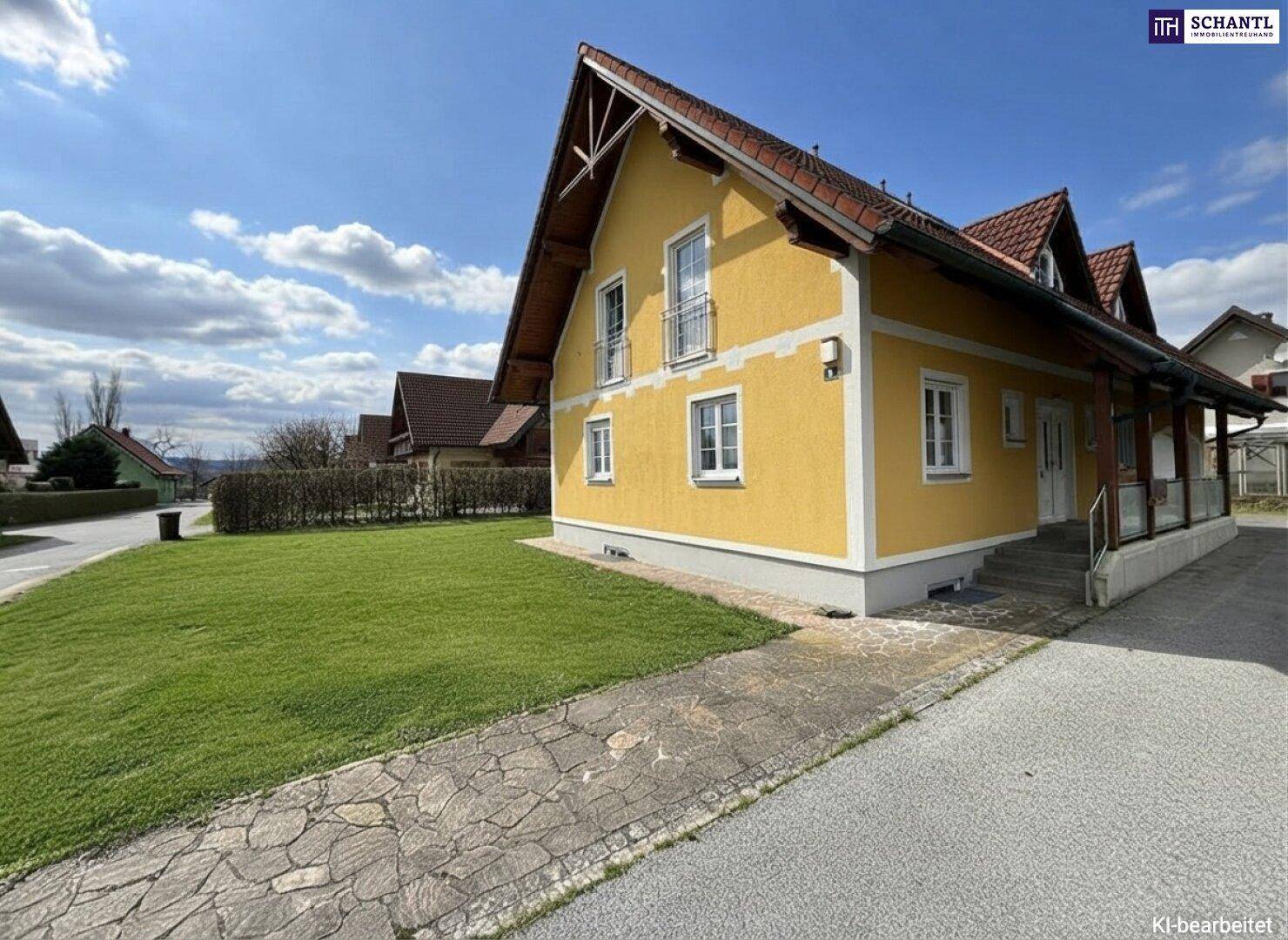 Seitenansicht des Hauses mit Eingangsbereich, gepflastertem Weg und gepflegtem Rasen.