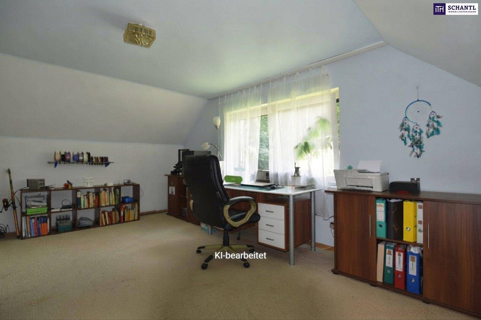 Helles Dachgeschossbüro mit Schreibtisch, Bücherregalen und Teppichboden, gut beleuchtet durch ein großes Fenster.