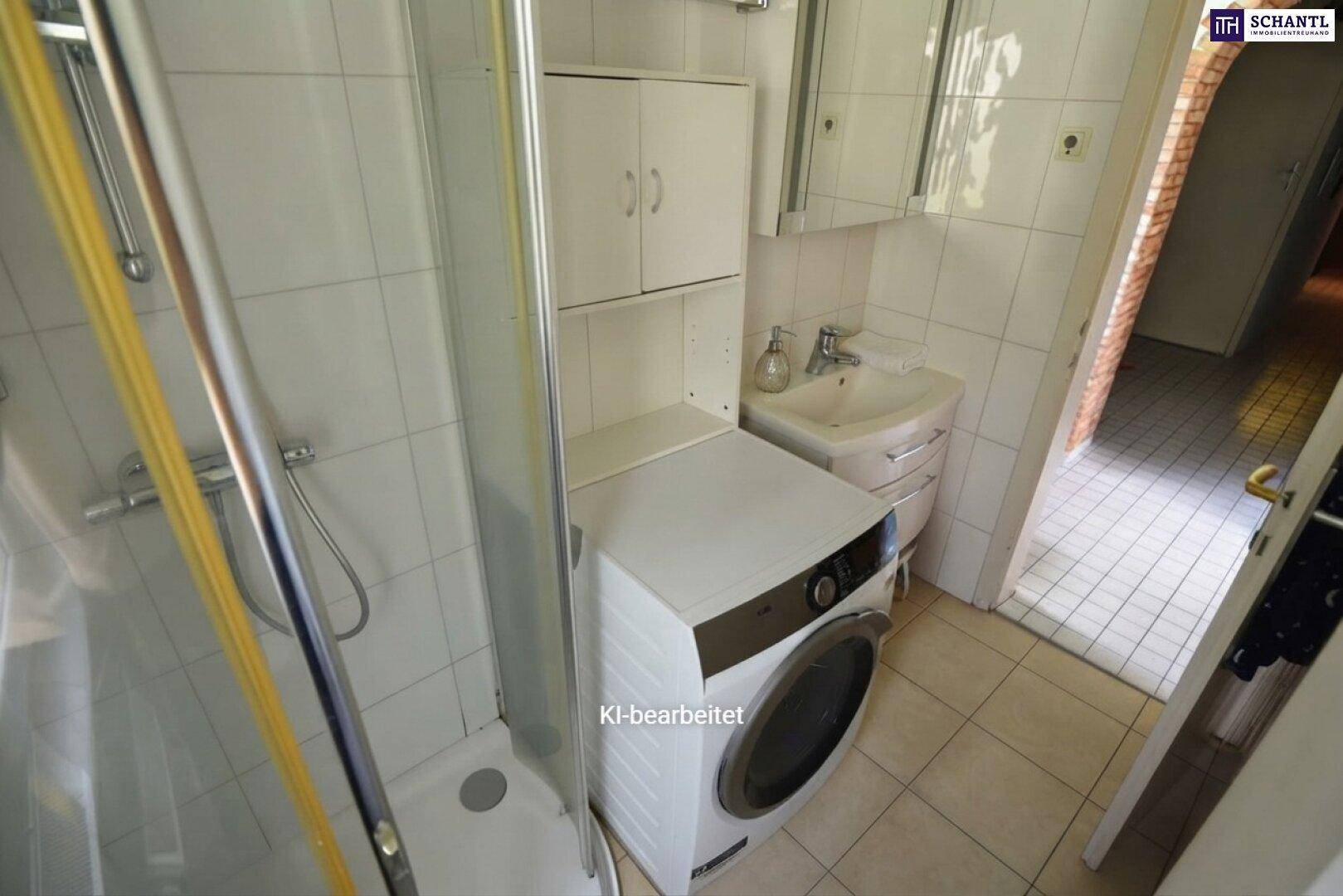 Kleines Badezimmer mit Dusche, Waschbecken und integrierter Waschmaschine, gefliest in Weiß.