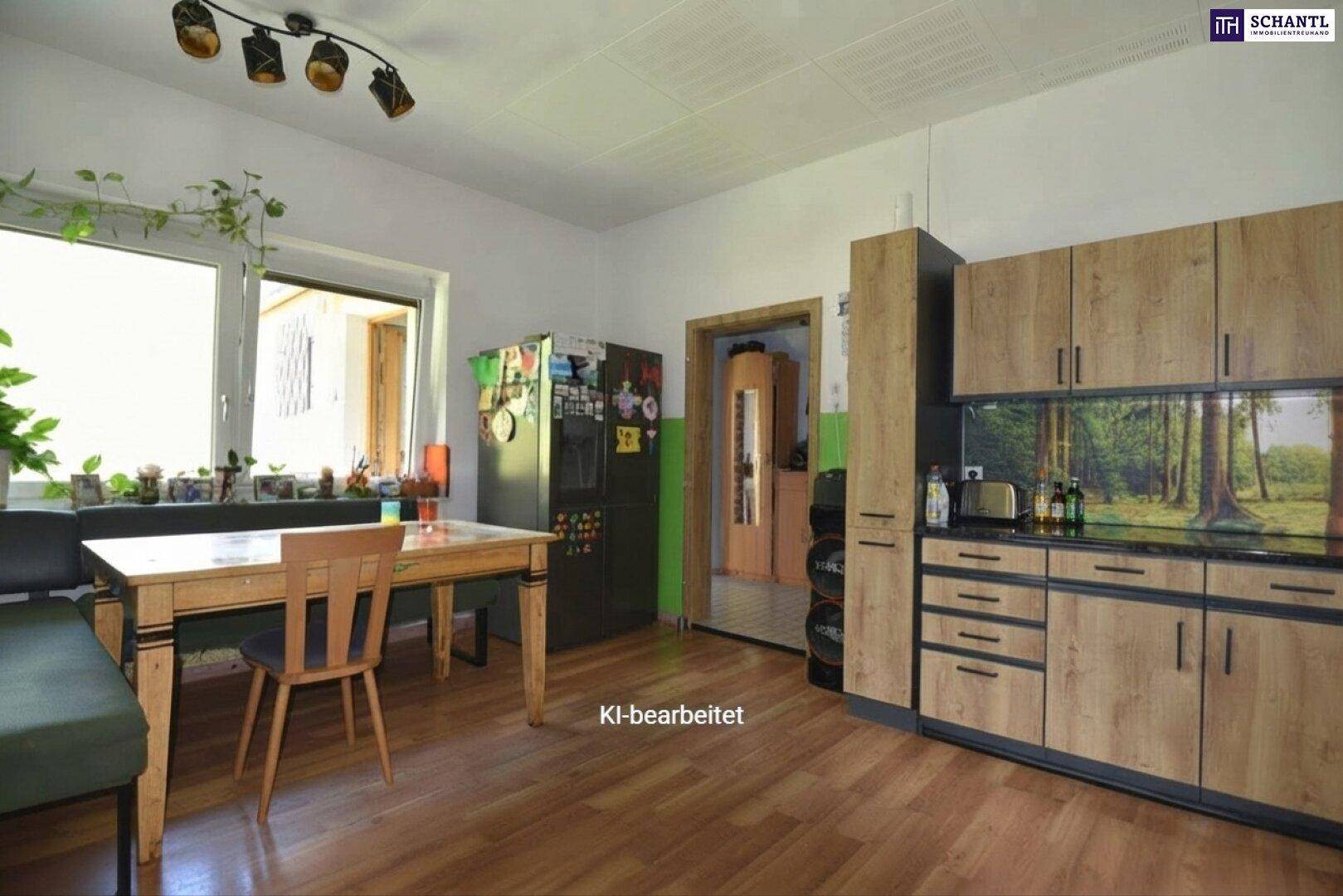 Funktionale Küche mit Holzelementen, Esstisch und Blick ins Grüne durch ein großes Fenster.