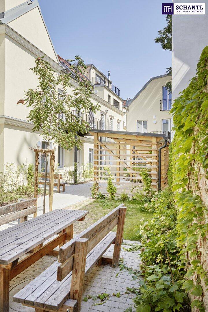 Grüner Innenhof mit Holzbänken, Tischen und üppiger Vegetation.