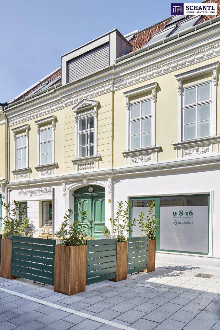 Seitenansicht der historischen Fassade mit Geschäften im Erdgeschoss und Dachfenstern.
