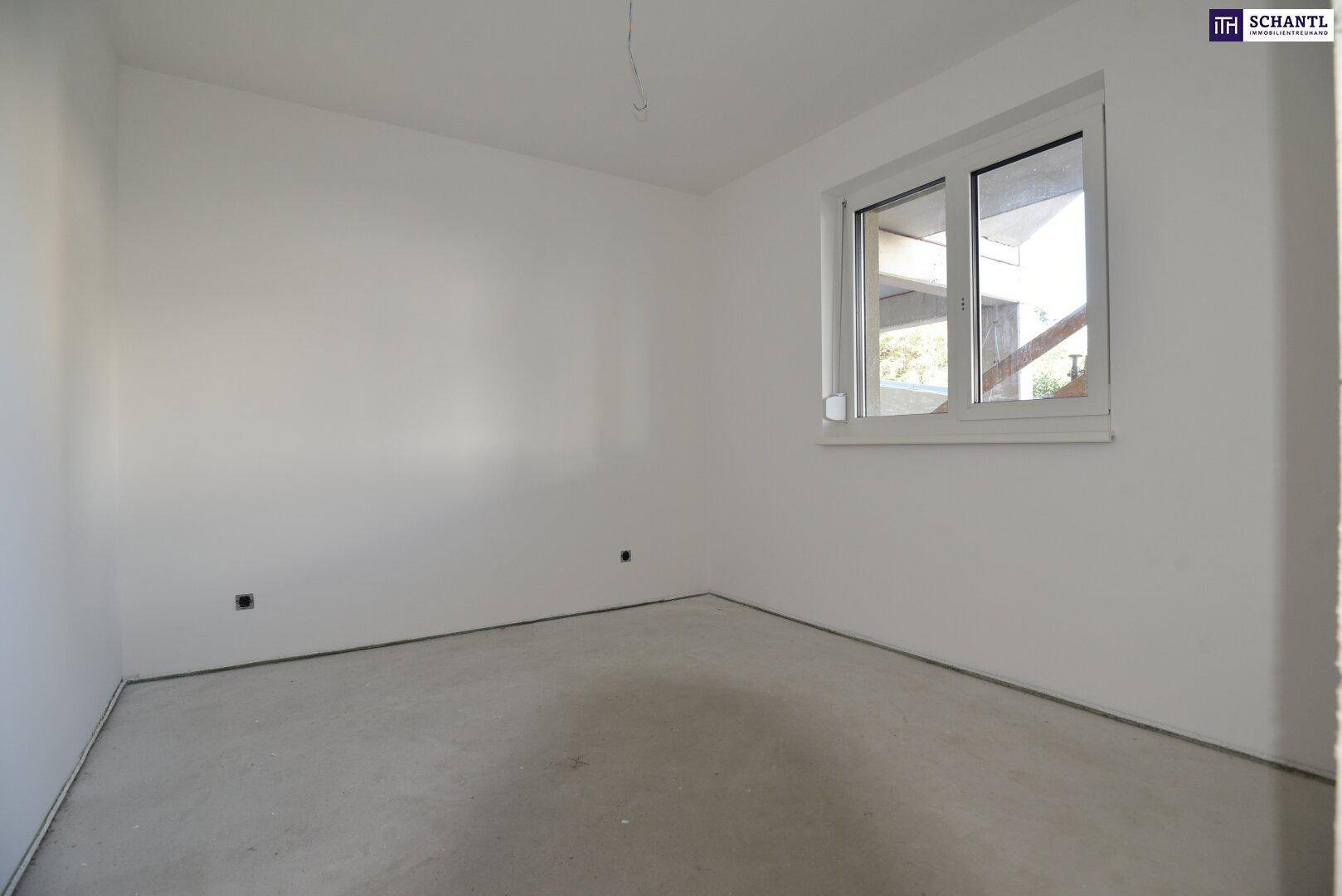Helles Zimmer im Rohbau mit weiß gestrichenen Wänden und einem großen Fenster für viel Tageslicht.