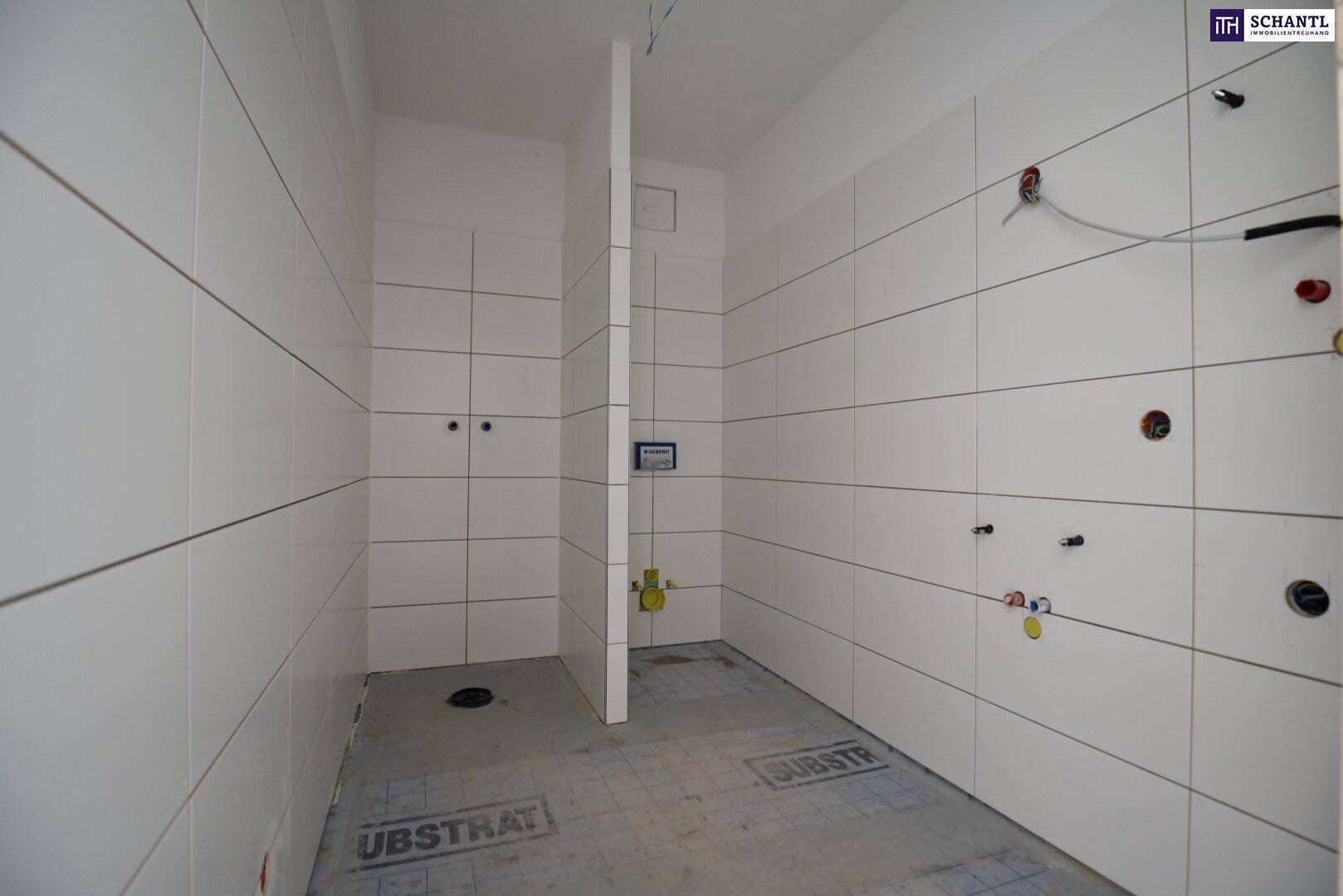 Unfertiges Badezimmer mit weißen Fliesen und sichtbaren Rohinstallationen für Dusche und WC.