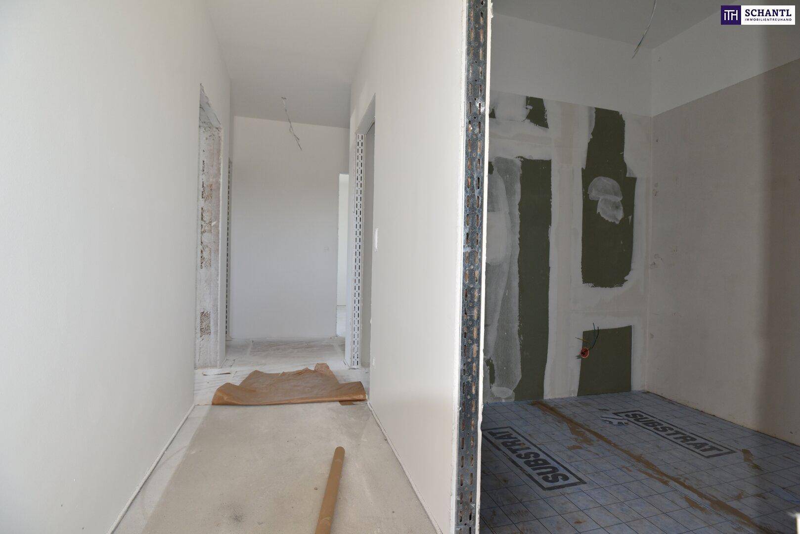 Flur und angrenzender Raum im Rohbau mit sichtbaren Installationsvorbereitungen.