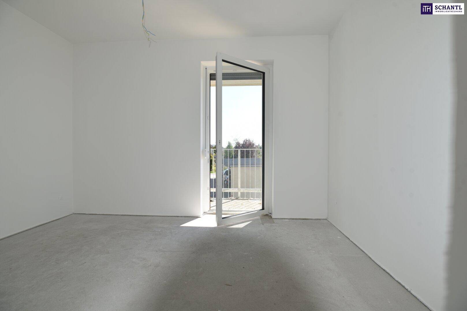 Leerer Raum im Rohbau mit Zugang zu einem Balkon und viel Tageslicht.