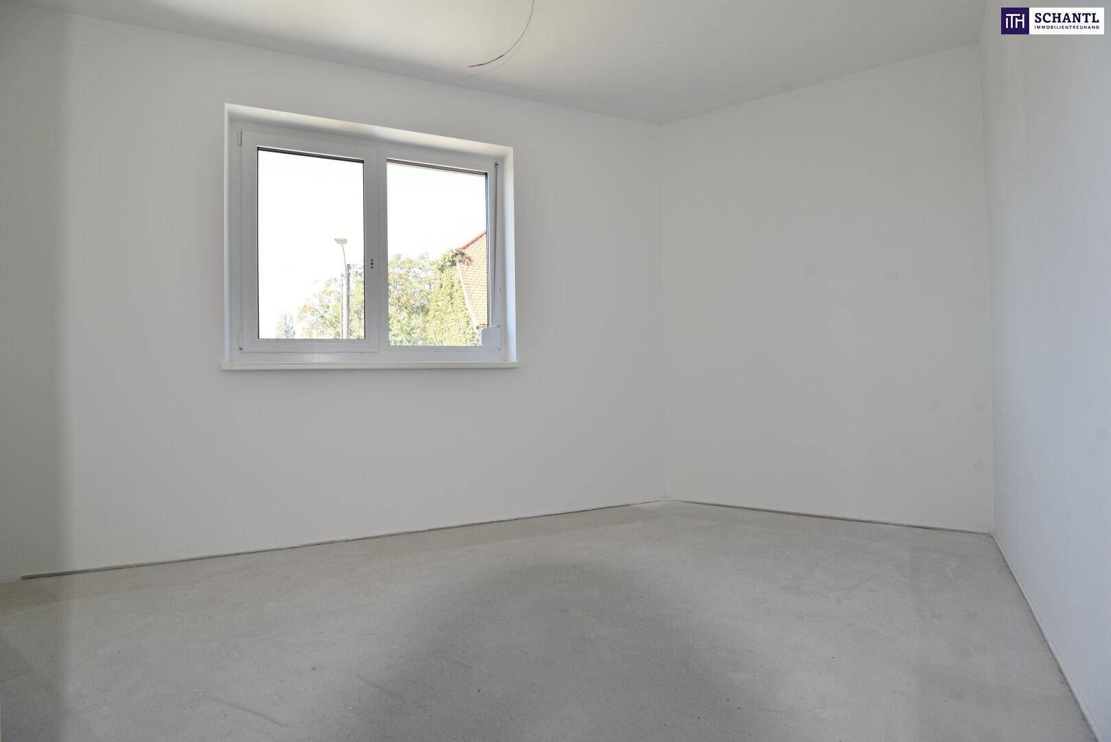 Unmöblierter Raum im Neubau mit einem großen Fenster und hellen Wänden.