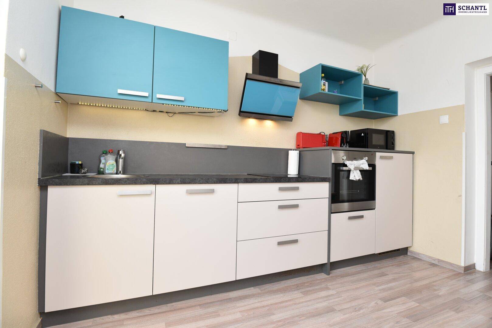 Moderne Küche mit hellen Unterschränken, blauen Oberschränken und integriertem Backofen.
