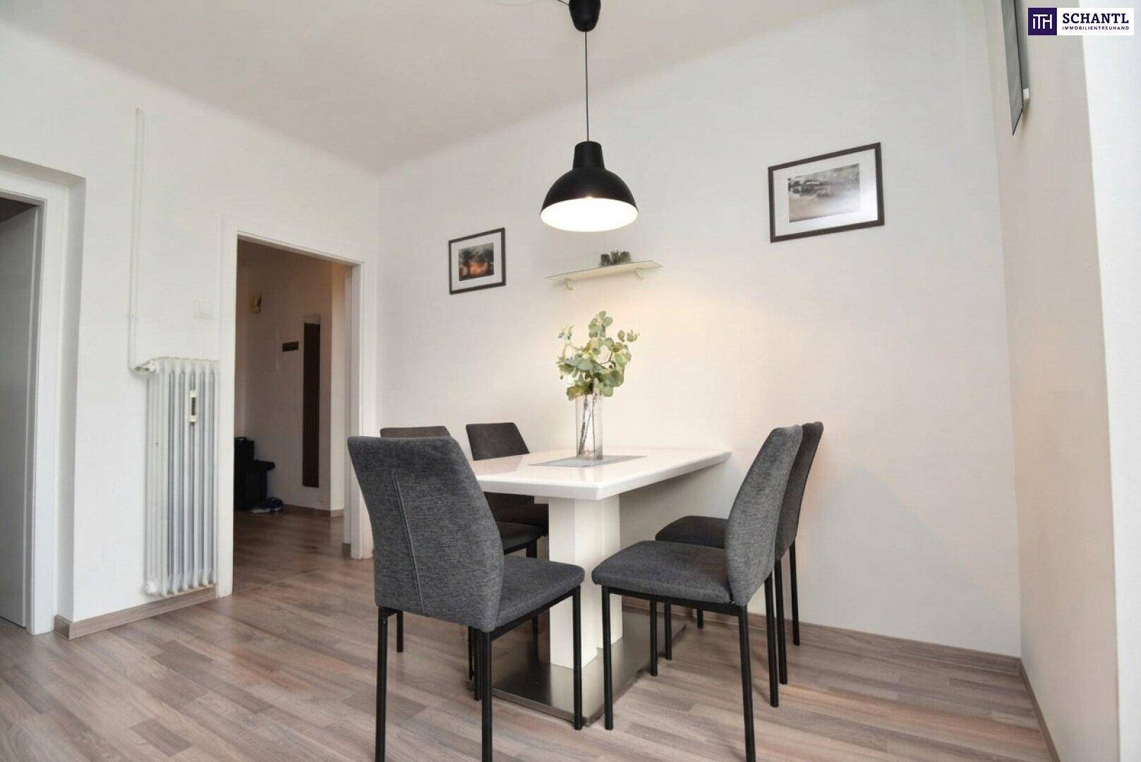 Essbereich mit modernem weißen Tisch und vier grauen Stühlen, daneben ein Heizkörper.