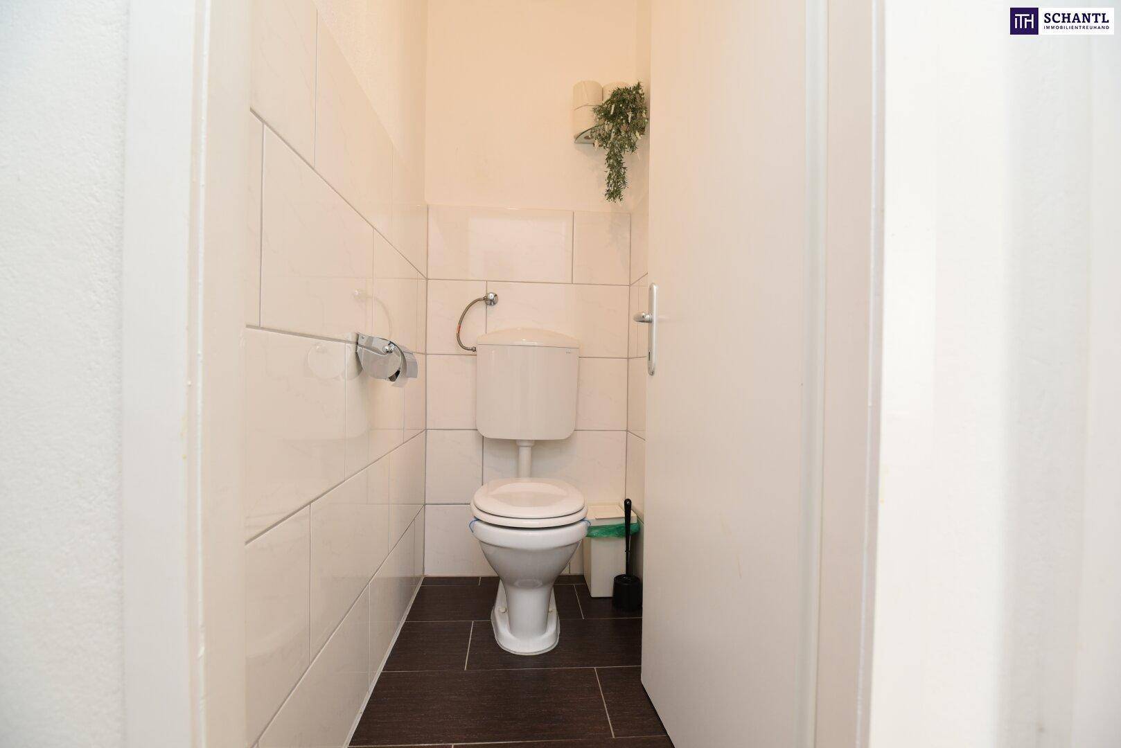 Separates WC mit Toilette und hellen Fliesen an Wänden und Boden.