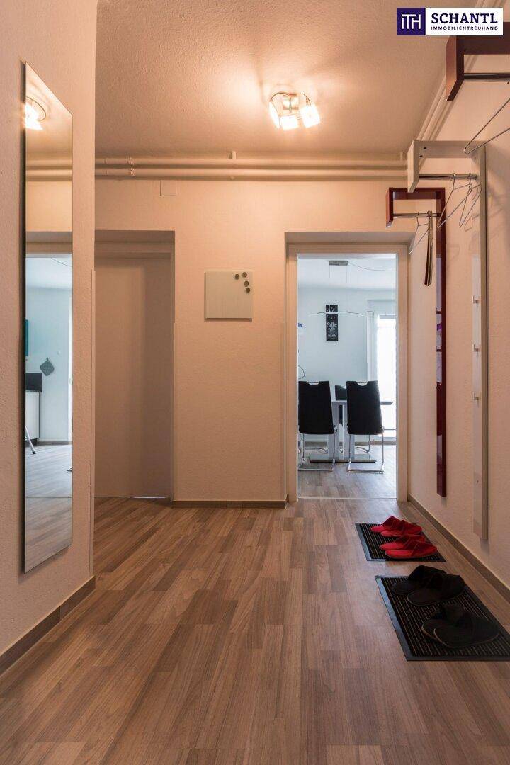 Heller Flur mit Laminatboden und großem Spiegel, der zu weiteren Räumen führt.