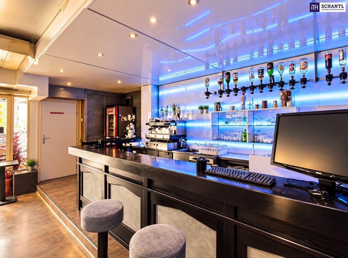 Moderne Bar mit beleuchteter Rückwand, Kaffeemaschine und professioneller Ausstattung.