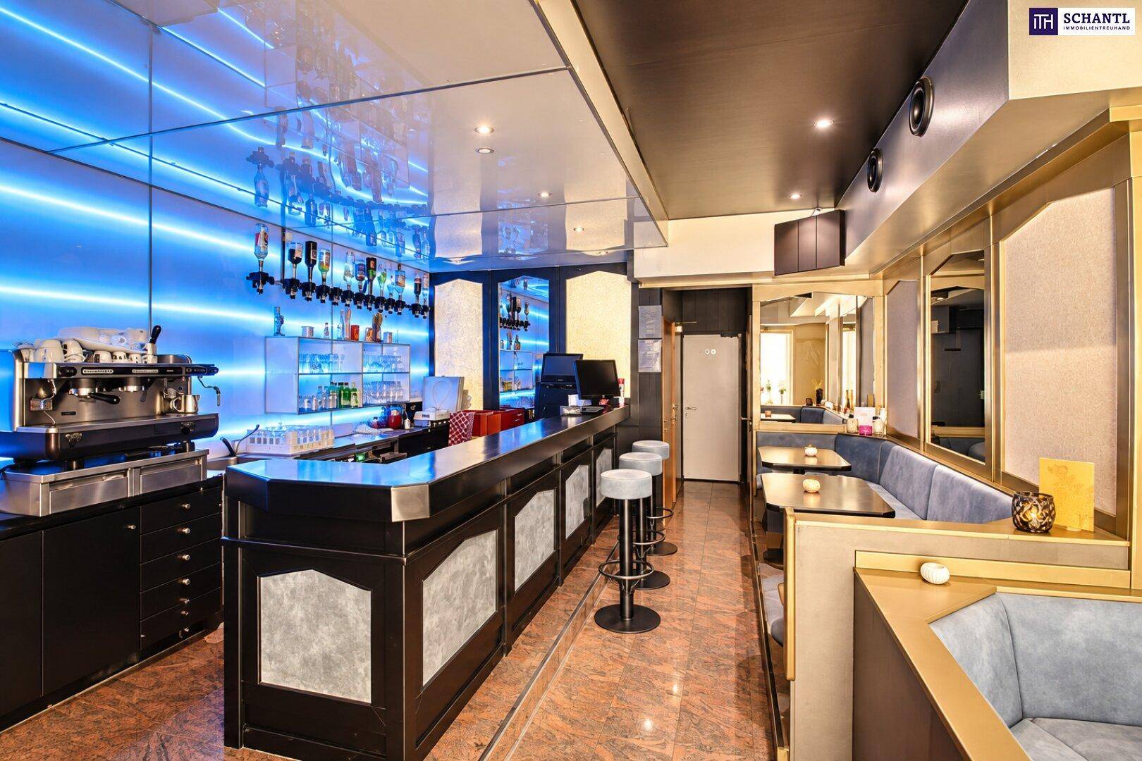 Stilvolle Bar mit blauer LED-Beleuchtung, Espresso-Maschine und Blick auf den Sitzbereich.