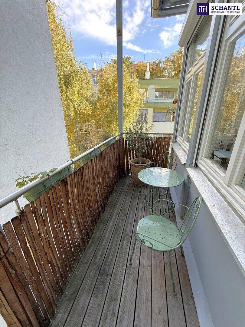 Kleiner Balkon mit Holzboden, Sitzgelegenheiten und Blick ins Grüne.