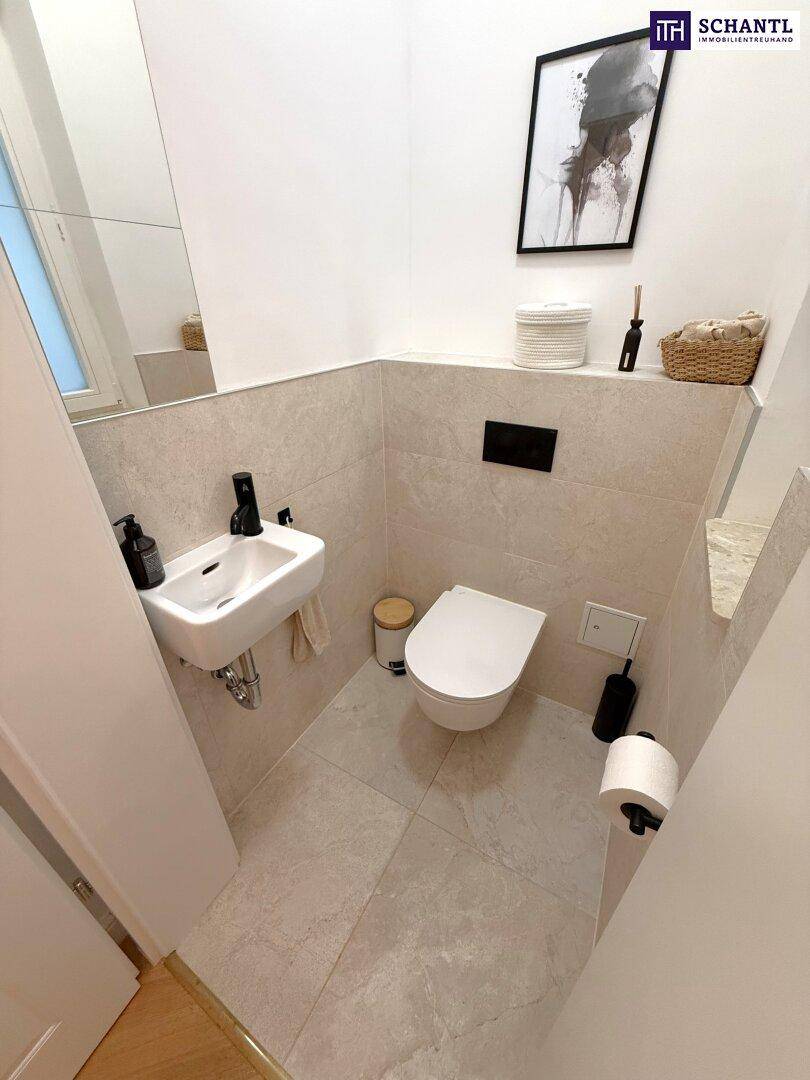 Kleines Gäste-WC mit wandhängender Toilette, kleinem Waschbecken und modernen Fliesen.