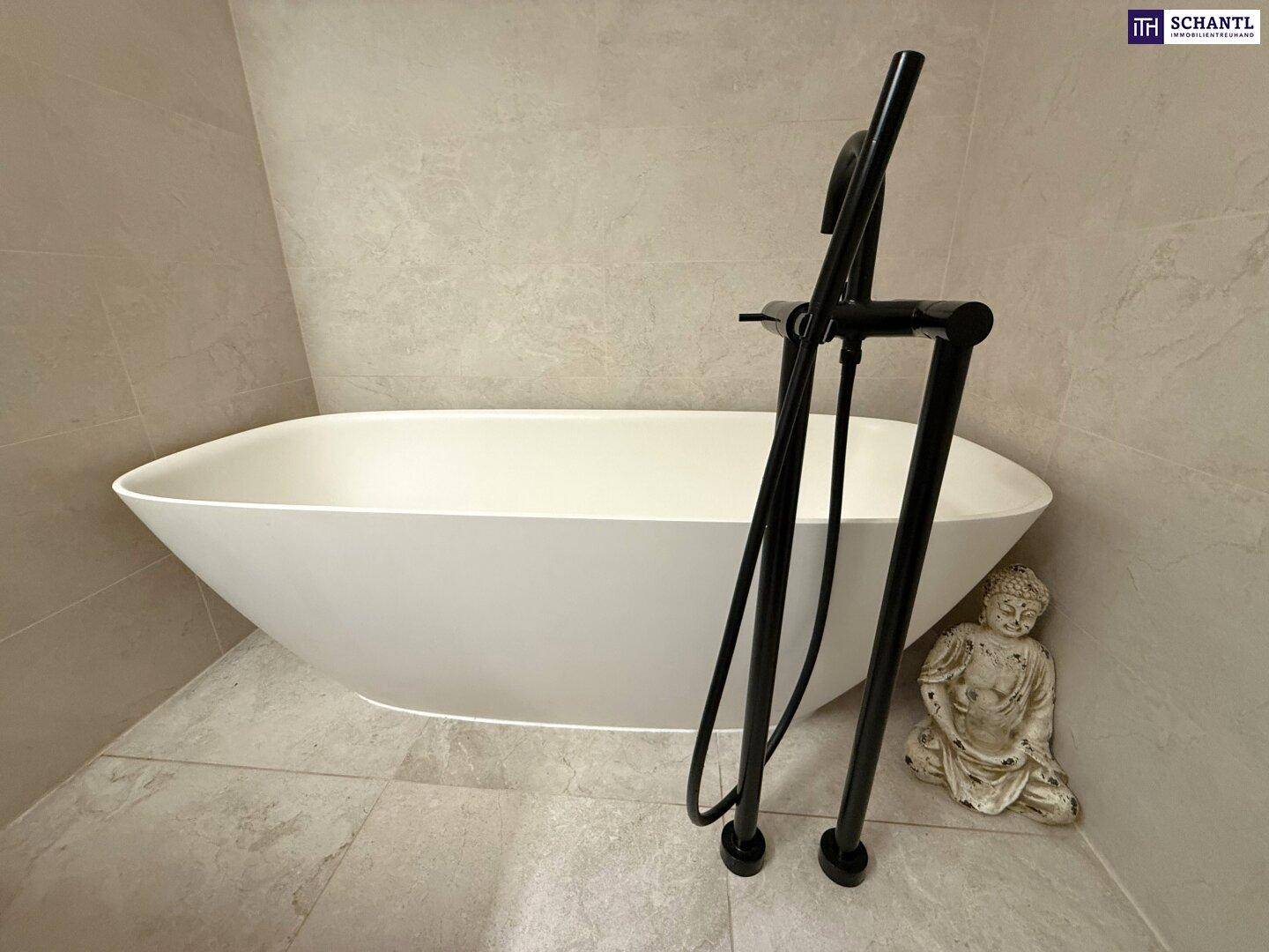Elegante freistehende Badewanne mit schwarzen Armaturen in einem modern gefliesten Badezimmer.