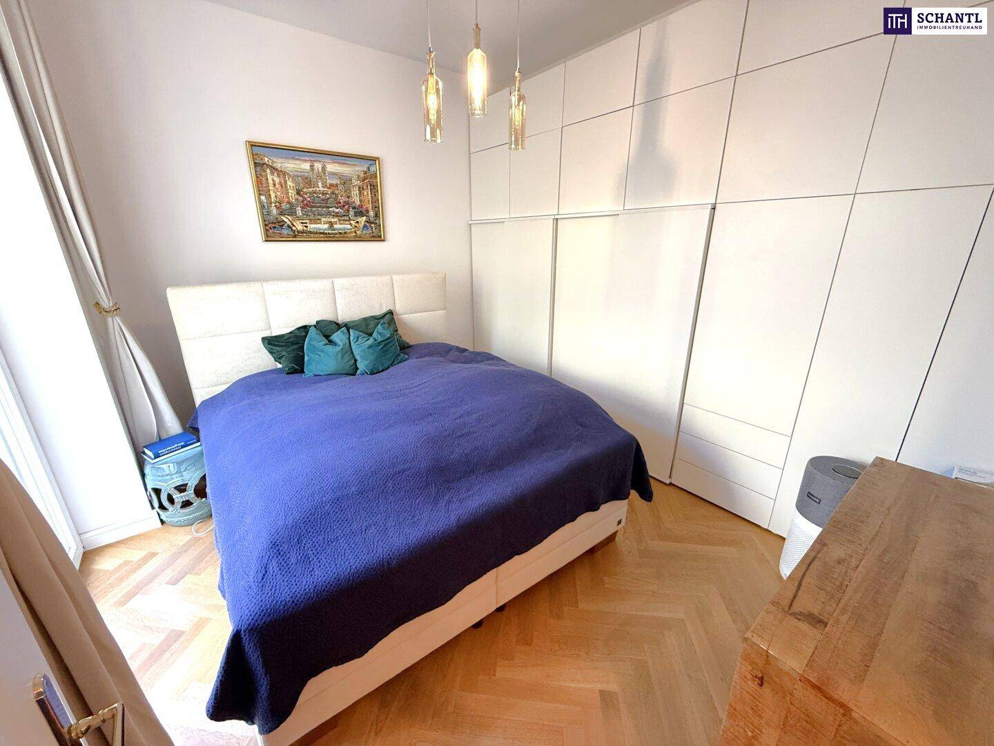 Gemütliches Schlafzimmer mit großem Bett, Einbauschränken und elegantem Fischgrätparkett.