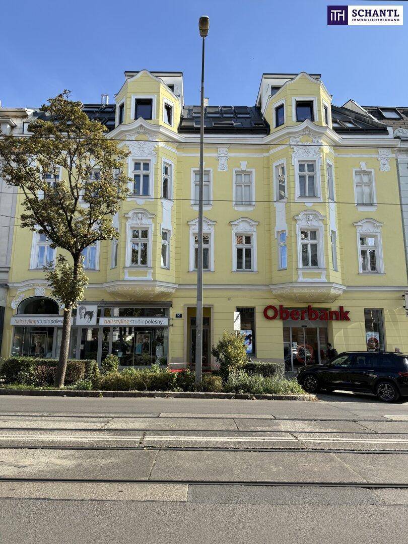Historisches Gebäude mit gelber Fassade und Geschäften im Erdgeschoss an einer belebten Straße.