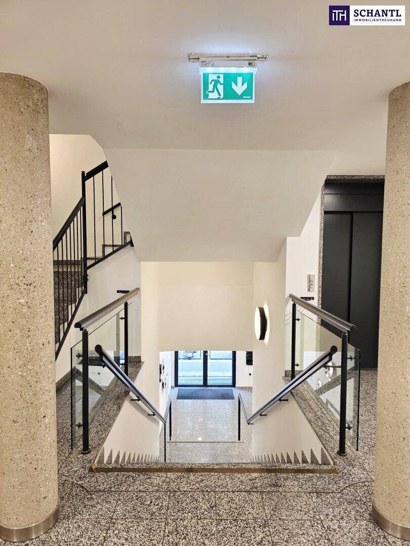Blick vom Treppenhaus nach unten zum Eingangsbereich mit Aufzug und Granitboden.