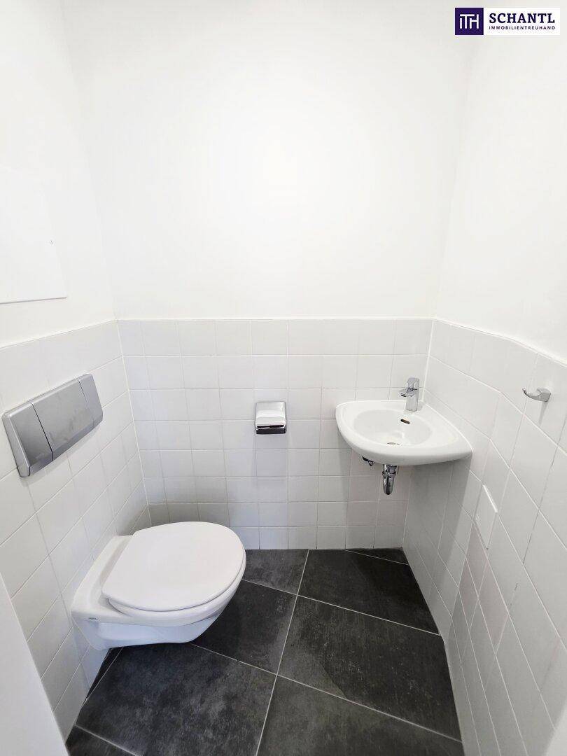 Kleines Gäste-WC mit wandhängender Toilette, Eckwaschbecken und modernen Fliesen.
