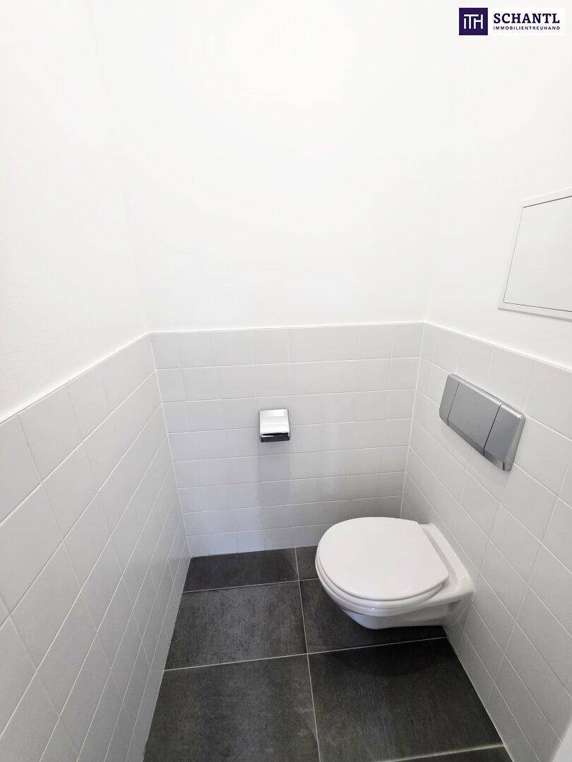 Sauberes Gäste-WC mit wandhängender Toilette und modernen weißen Fliesen an den Wänden.