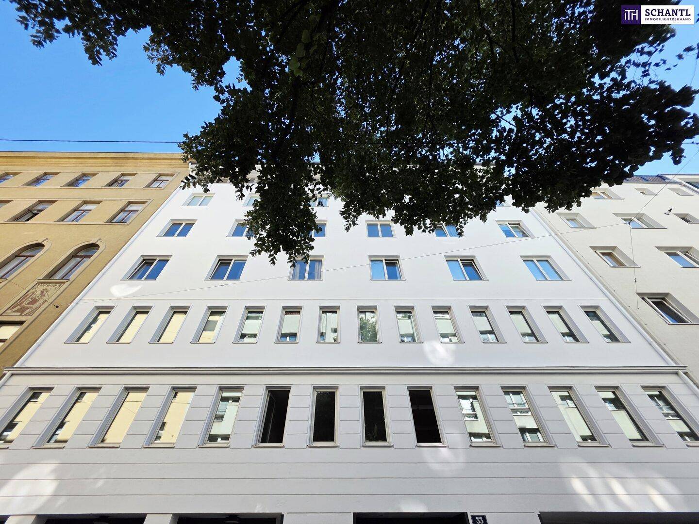 Moderne weiße Gebäudefassade mit zahlreichen Fenstern und klarem Himmel.