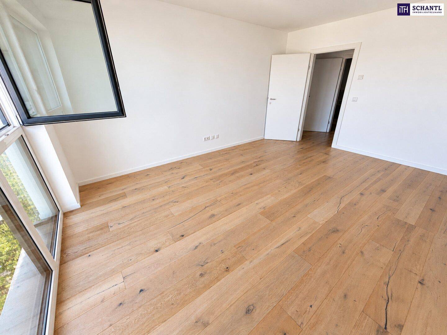 Helles Schlafzimmer mit Holzboden und großem Fenster, das eine angenehme Atmosphäre schafft.