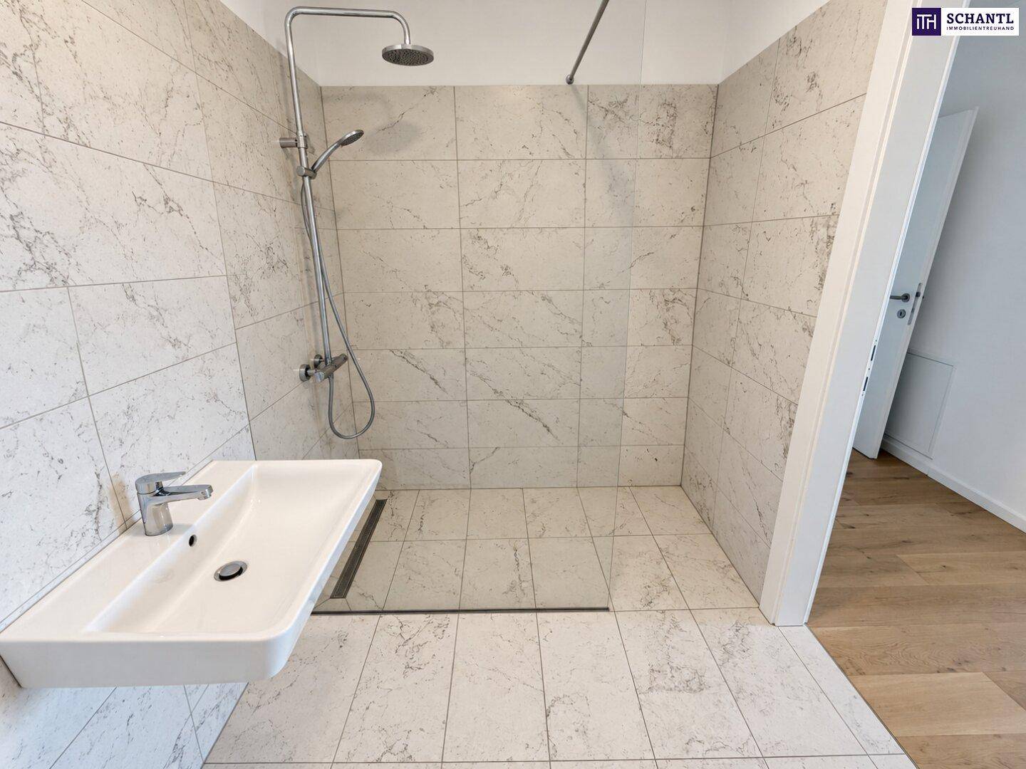 Modernes Badezimmer mit ebenerdiger Dusche, eleganten Fliesen und minimalistischem Waschbecken.