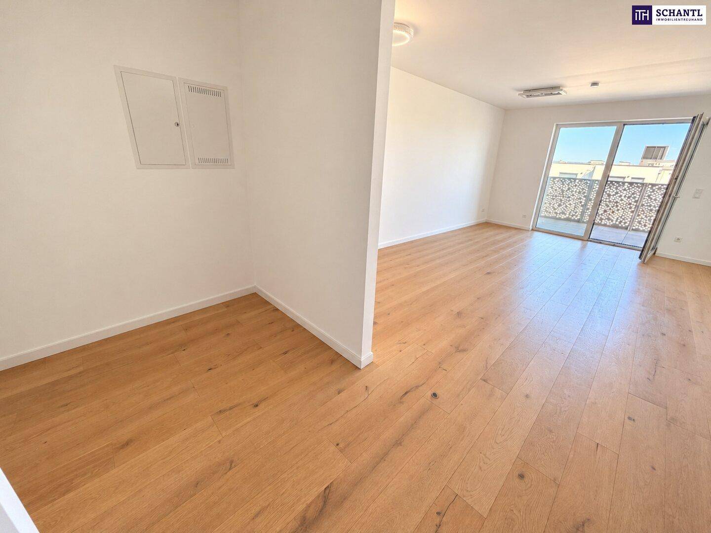 Geräumiger Wohnbereich mit Holzboden und Zugang zu einem Außenbereich, ideal für offenes Wohnen.