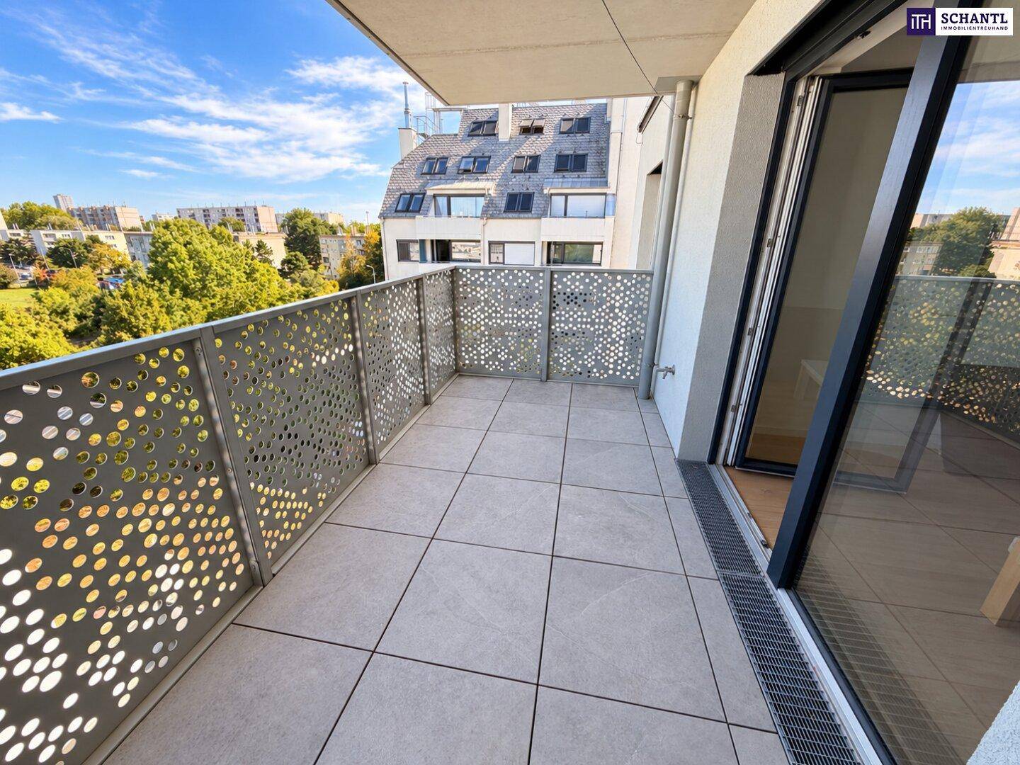 Geräumiger Balkon mit modernen Fliesen und perforiertem Metallgeländer, bietet einen Stadtblick.