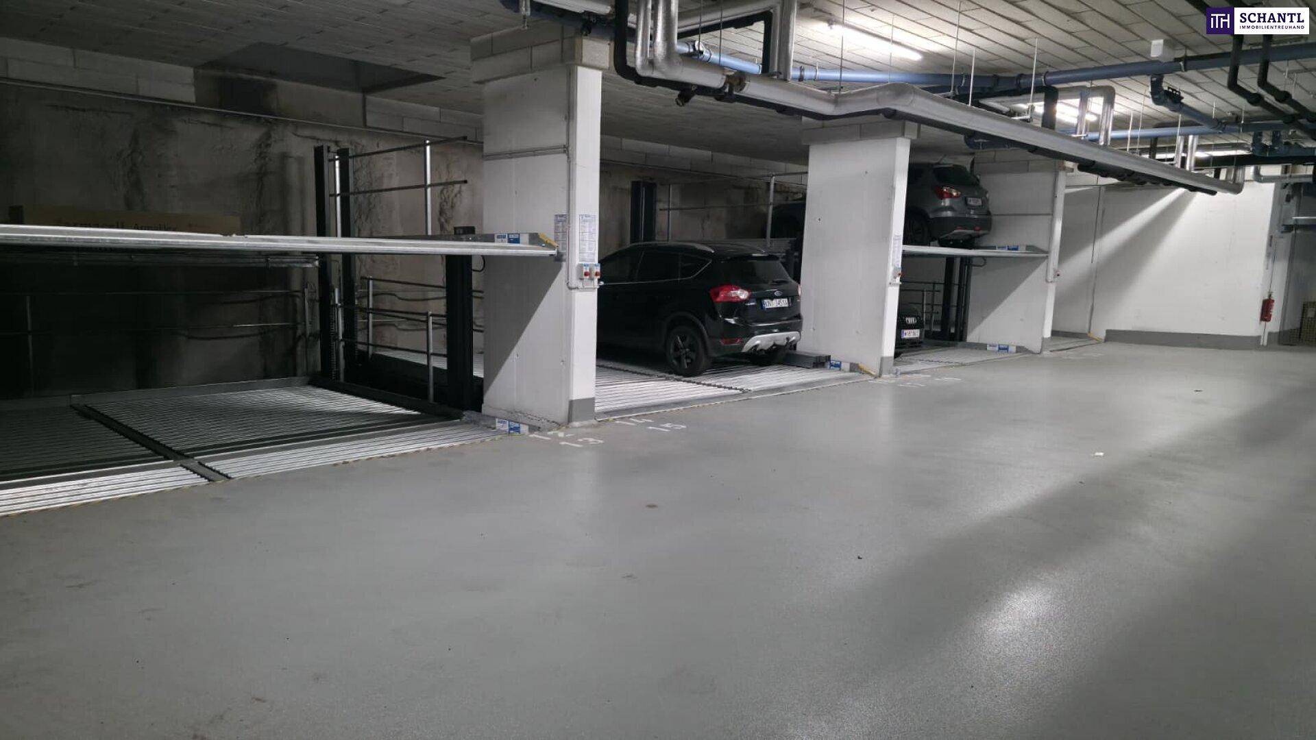 Weitläufige Tiefgarage mit mehreren automatischen Parksystemen und sichtbaren Installationen.