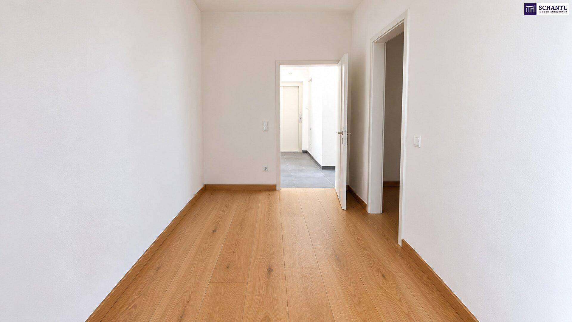Leerer Raum mit Holzboden und zwei offenen Türen, die zu weiteren Zimmern führen.