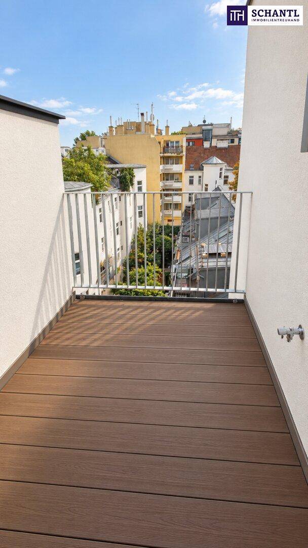Kleiner Balkon mit Holzboden und Blick auf die umliegenden Gebäude der Stadt.