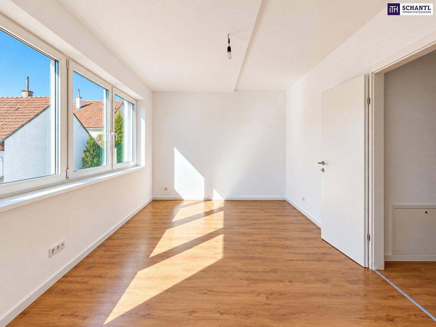 Helles Schlafzimmer mit Laminatboden und großen Fenstern, die viel Tageslicht hereinlassen.