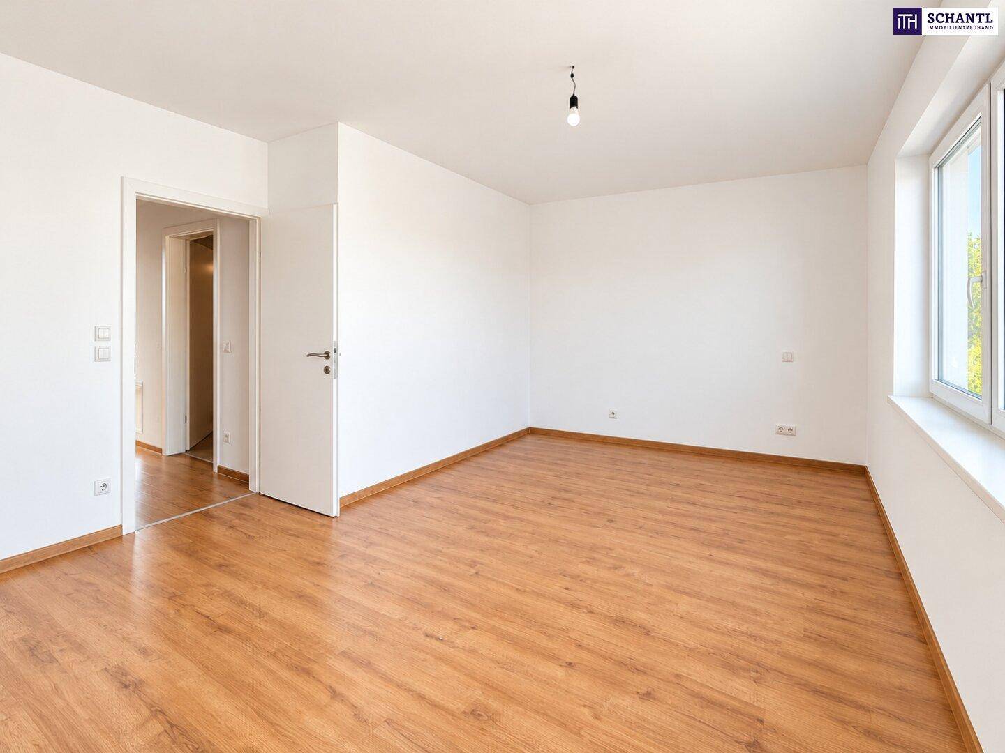 Geräumiges Schlafzimmer mit Laminatboden und Zugang zu einem weiteren Raum.