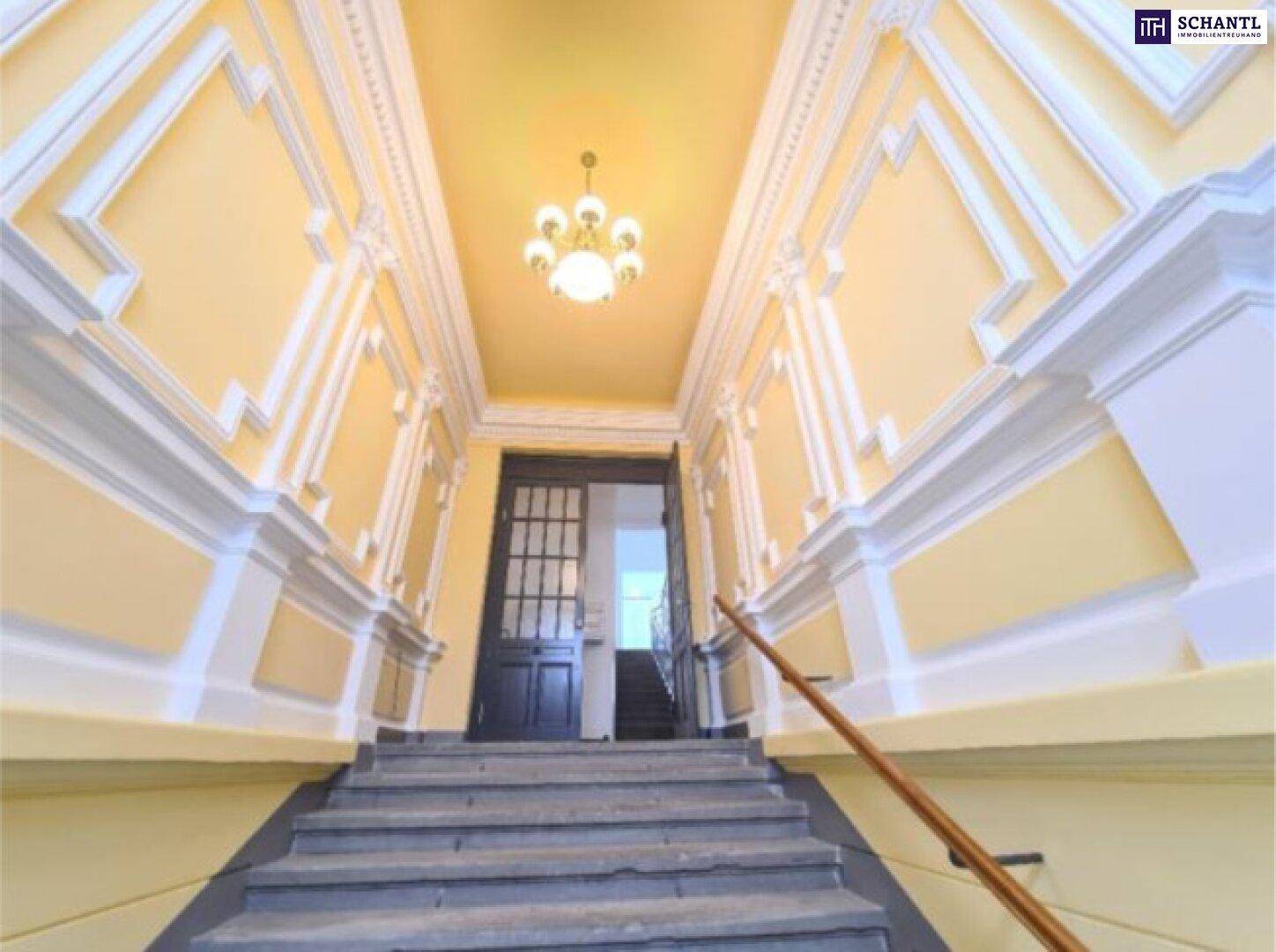 Repräsentatives Treppenhaus mit Stuckverzierungen und klassischem Kronleuchter im Altbau.