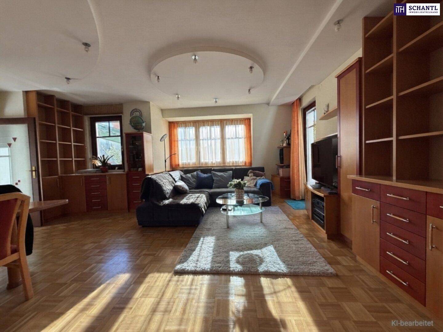 Geräumiger Wohnbereich mit Parkettboden, bequemer Couch und umfangreichen Holzregalen.