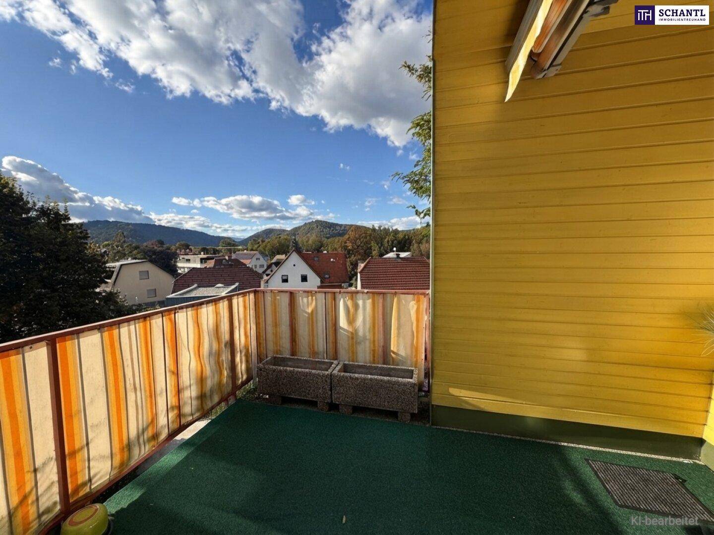 Heller Balkon mit Kunstrasen und Sichtschutz, bietet einen weiten Blick auf die Berglandschaft.